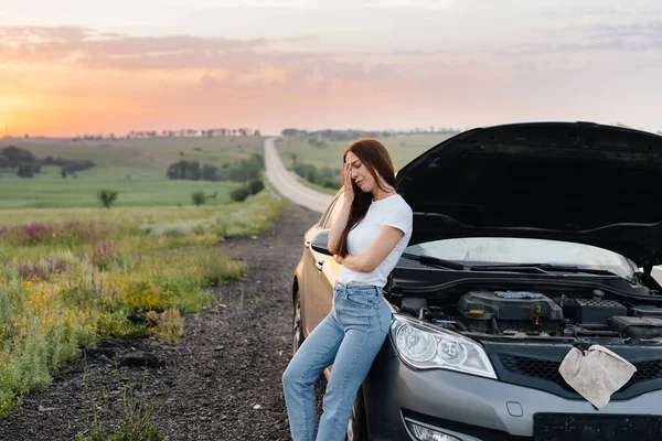落日时分 一个沮丧的小女孩站在高速公路中央一辆抛锚的汽车旁边 汽车的故障和修理 等人帮忙 — 图库照片