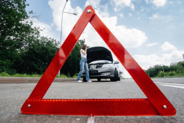 Genç bir kız otoyolun ortasında bozuk bir arabanın yanında duruyor ve telefondan yardım istiyor. Aracın bozulması ve arızası. Yardım bekliyorum..