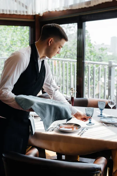 Jovem Garçom Uniforme Elegante Está Envolvido Servir Mesa Belo Restaurante — Fotografia de Stock