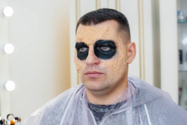 Cadılar Bayramı tatili için stüdyoda, kafatası şeklinde güzel, ürkütücü makyajlı genç bir adam. Mutlu Cadılar Bayramı konsepti.