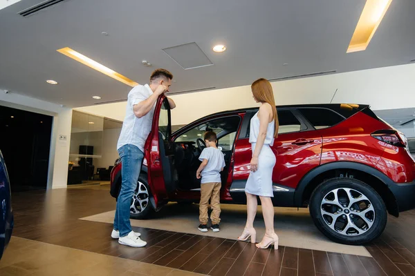 一个快乐的年轻家庭在一家汽车经销店选择并购买一辆新车 买一辆新车 — 图库照片