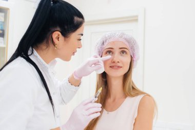 Genç ve güzel bir kız için burun boşluğunu doldurmak ve göz çevresindeki mezoterapi için kozmetik prosedür. Modern kozmetoloji.