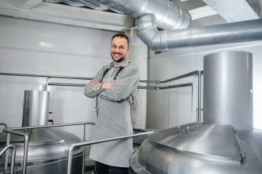 Genç bir erkek bira imalatçısı küçük bir bira fabrikasında demleme işlemiyle meşgul. Bira üretimi.