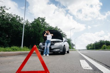 Genç bir kız otoyolun ortasında bozuk bir arabanın yanında duruyor ve telefondan yardım istiyor. Aracın bozulması ve arızası. Yardım bekliyorum..