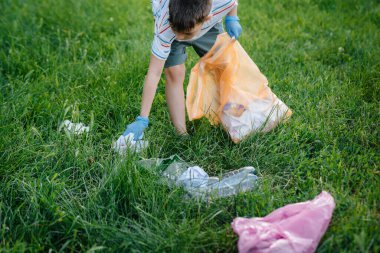 Gün batımında yedi yaşında bir çocuk parkta çöp toplamakla meşgul. Çevre bakımı, geri dönüşüm.