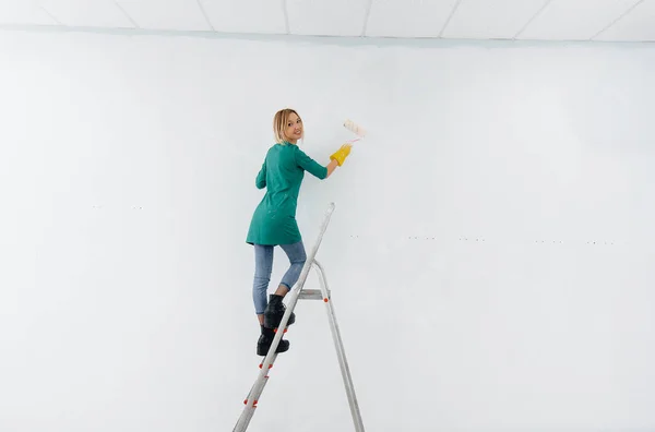 Una Joven Sobre Una Escalera Pinta Una Pared Blanca Con — Foto de Stock