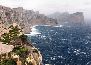 Fırtına Denizi 'nde, bulutlu bir kış gününde Mallorca adasındaki Cape Formentor' daki kayalıklara vuran dalgalar...