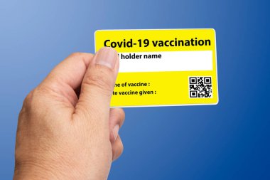 Stüdyo fotoğrafında elinde covid-19 aşı kartı olan biri var..