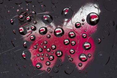 Çizgili kırmızı-siyah-beyaz küreler bir kelebeğin beyaz-pembe silüetiyle antrasit arka planına karşıdır. Soyut fantezi. 