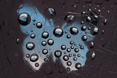 Çizgili siyah-beyaz-mavi küreler bir kelebeğin mavi silüetiyle antrasit arka planına karşıdır. Soyut fantezi. 