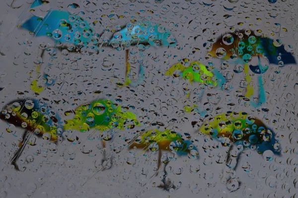 Rain. Raindrops fall on a gray background with blue and green silhouettes of umbrellas and their reflections. Abstract fantasy. 3D render.