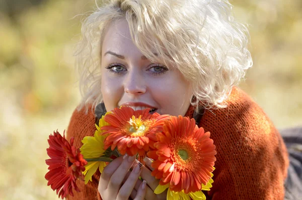 Hermosa mujer retrato al aire libre en un día soleado y flores rojas —  Fotos de Stock