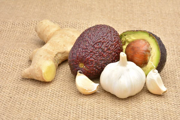 Avocado and garlic on old canvas background — Stock Photo, Image