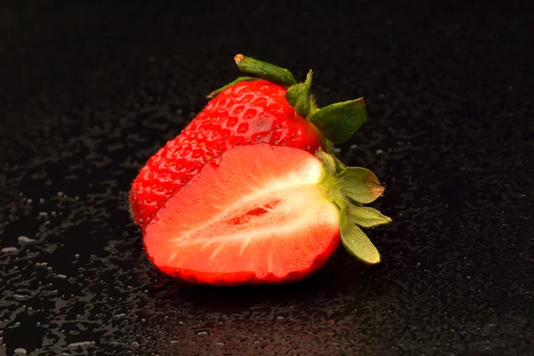 Frech jordgubbar med blad på svart bakgrund — Stockfoto