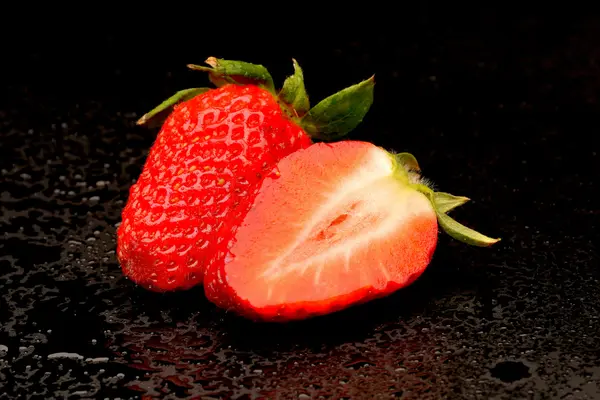 Frech Erdbeeren mit Blättern auf schwarzem Hintergrund — Stockfoto