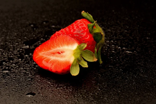 Frech Erdbeeren mit Blättern auf schwarzem Hintergrund — Stockfoto