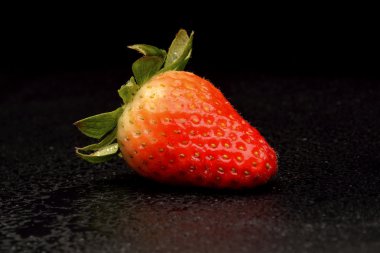 Siyah arka plan üzerine yaprakları ile taze çilek