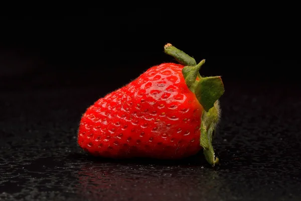 Frech jordgubbar med blad på svart bakgrund — Stockfoto