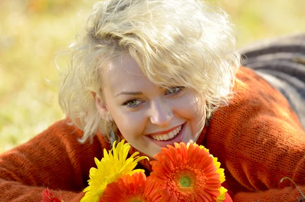 Hermosa mujer retrato al aire libre en un día soleado y flores rojas — Foto de Stock