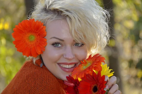 Beautiful woman outdoor portrait on a sunny day and red flowers — Stock Photo, Image