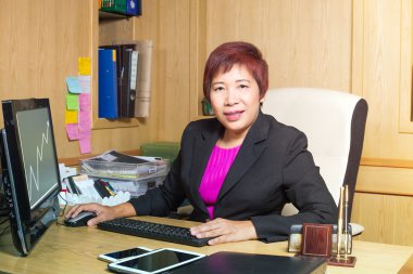 iş kadın Asya Yöneticisi üst düzey yaş masanın üzerinde siting zarif bakmak