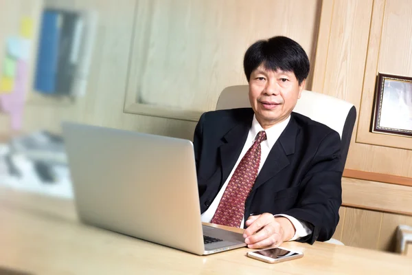 业务人亚洲经理高级年龄选址在桌上看起来优雅 — 图库照片
