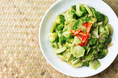 Stir Fried brokoli (Pad Pak) Tay geleneksel gıda sıcak ve baharatlı içinde beyaz plaka üzerinde Hasır arka plan