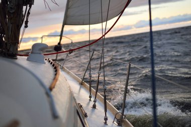 Bir kış günü açık denizde yat gezintisi. Güverteden pruvaya, direğe ve yelkenlere yakın görüntü. Dramatik fırtınalı gökyüzü, kara bulutlar. Destansı deniz manzarası. Kuzey denizi, Norveç