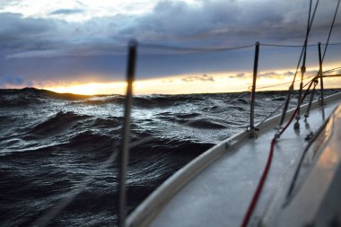 Günbatımında bir yelkenliden Kuzey Denizi manzarası. Çarpıcı fırtınalı gökyüzü, kara bulutların arasından güneş ışınları. Destansı deniz manzarası. Kışın şiddetli kasırga. Norveç