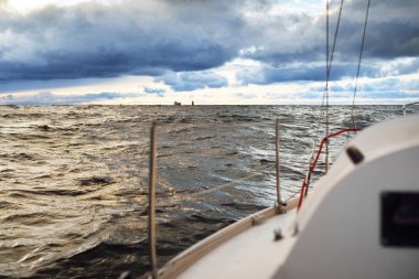 Gün batımında açık denizde yelken açmak. Güverteden pruvaya, direğe ve yelkenlere yakın görüntü. Dramatik fırtınalı gökyüzü, kara bulutlar, kış kasırgası, sert hava. Destansı deniz manzarası. Kuzey denizi, Norveç