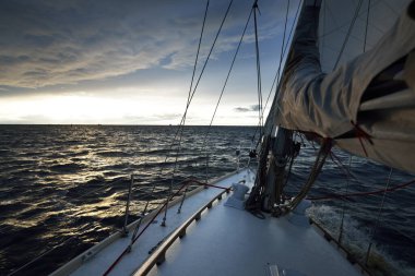 Bir kış günü açık denizde yat gezintisi. Güverteden pruvaya, direğe ve yelkenlere yakın görüntü. Dramatik fırtınalı gökyüzü, kara bulutlar. Destansı deniz manzarası. Kuzey denizi, Norveç