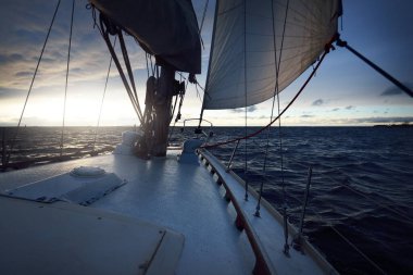 Gün batımında açık denizde yelken açmak. Güverteden pruvaya, direğe ve yelkenlere yakın görüntü. Dramatik fırtınalı gökyüzü, kara bulutlar, kış kasırgası, sert hava. Destansı deniz manzarası. Kuzey denizi, Norveç
