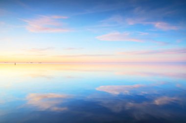 Gün batımında donmuş Saima gölünün karla kaplı kıyılarının panoramik görüntüsü. Göz kamaştırıcı pembe bulutlar. Suyun simetri yansımaları. Kış Harikalar Diyarı. Finlandiya