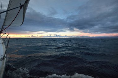 Günbatımında bir yelkenliden Kuzey Denizi manzarası. Çarpıcı fırtınalı gökyüzü, kara bulutların arasından güneş ışınları. Destansı deniz manzarası. Kışın şiddetli kasırga. Norveç. Görüntü, iklim değişikliği, ekoloji