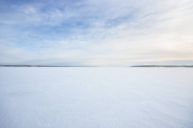 Donmuş karla kaplı göl, açık mavi gökyüzünün altında, sirrus bulutlarıyla. Taze kar dokusu. Kuzey Kutbu, Laponya. Küresel ısınma, kış sporu ve balıkçılık, çevre koruma teması