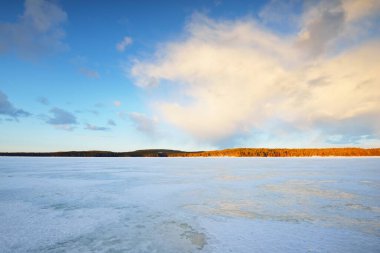 Gün batımında donmuş göl ve karla kaplı çam ormanı. Buz dokusu. Dramatik gökyüzü, yumuşak güneş ışığı. Idyllic kış sahnesi. Doğa, çevre koruma, ekoloji, iklim değişikliği, eko-turizm, Noel