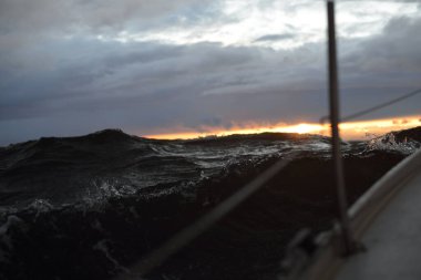 Günbatımında bir yelkenliden Kuzey Denizi manzarası. Çarpıcı fırtınalı gökyüzü, kara bulutların arasından güneş ışınları. Destansı deniz manzarası. Kışın şiddetli kasırga. Norveç