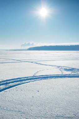 Gün doğumunda donmuş orman gölü, donmakta olan ağaçlar. Taze karda bisiklet, kayak ve insan izleri. Idyllic kırsal kesim. Mavi gökyüzü, öğlen güneşi. Doğa, ekoloji, küresel ısınma, Noel temaları