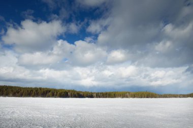 Gün batımında donmuş göl ve çam ormanı. Buz dokusu. Dramatik fırtınalı mavi gökyüzü, destansı bulutlar. Kış Harikalar Diyarı. Doğa, ekoloji, iklim değişikliği, eko-turizm, kararsız hava