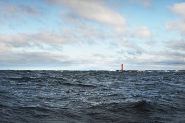 Fırtınadan sonra kara bulutların altında bir deniz feneri. Yelkenli teknenin manzarası. Dramatik fırtınalı gökyüzü. Destansı bulut manzarası. Kuzey denizi, Norveç. Kışın kasırga. Ekoloji, küresel ısınma kavramları