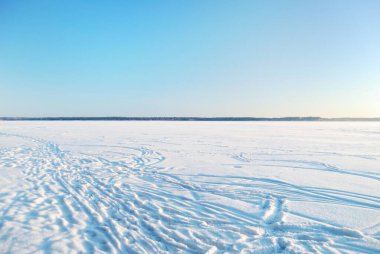 Güneşli bir günde donmuş orman gölü, donmakta olan ağaçlar, taze kar altında kayak ve insan izleri. Idyllic kırsal kesim. Açık mavi gökyüzü. Doğa, ekoloji, iklim değişikliği, küresel ısınma, Noel temaları