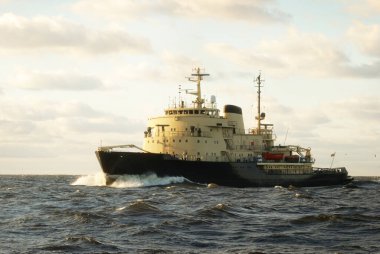 Sovyet buzkıranı dramatik günbatımı bulutları altında açık denizde. Yük taşımacılığı, küresel iletişim ve güvenlik, yakıt ve güç üretimi, sanayi, lojistik, araştırma, keşif