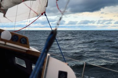 Gün batımında açık denizde yelken açmak. Güverteden pruvaya, direğe ve yelkenlere yakın görüntü. Dramatik fırtınalı gökyüzü, kara bulutlar, kış kasırgası, sert hava. Destansı deniz manzarası. Kuzey denizi, Norveç