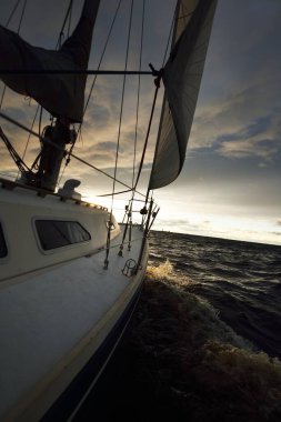 Gün batımında açık denizde yelken açmak. Güverteden pruvaya, direğe ve yelkenlere yakın görüntü. Dramatik fırtınalı gökyüzü, kara bulutlar, kış kasırgası, sert hava. Destansı deniz manzarası. Kuzey denizi, Norveç