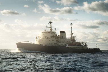 Sovyet buzkıranı dramatik günbatımı bulutları altında açık denizde. Yük taşımacılığı, küresel iletişim ve güvenlik, yakıt ve güç üretimi, sanayi, lojistik, araştırma, keşif