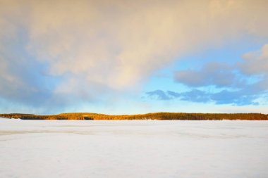 Gün batımında donmuş göl ve karla kaplı çam ormanı. Buz dokusu. Dramatik gökyüzü, yumuşak güneş ışığı. Idyllic kış sahnesi. Doğa, çevre koruma, ekoloji, iklim değişikliği, eko-turizm, Noel