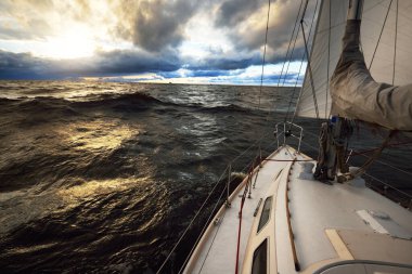 Bir kış günü açık denizde yat gezintisi. Güverteden pruvaya, direğe ve yelkenlere kadar yukarıdan aşağı görüş. Dramatik fırtınalı gökyüzü, kara bulutlar. Destansı deniz manzarası. Kuzey denizi, Norveç