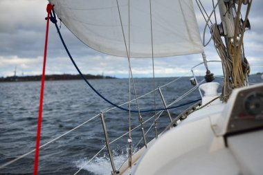 Norveç, gün batımında beyaz yat nehir limanından ayrılıyor. Güverteden pruvaya ve yelkenlere bir manzara. Fırtınadan sonra dramatik bir gökyüzü. Kış yelkeni. Boş zaman aktivitesi, eğlence teması