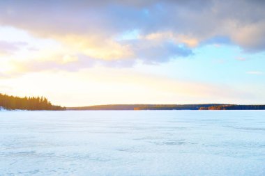 Gün batımında donmuş göl ve karla kaplı çam ormanı. Buz dokusu. Dramatik gökyüzü, pembe bulutlar. Kış Harikalar Diyarı. Doğa, çevre koruma, ekoloji, iklim değişikliği, eko-turizm, Noel