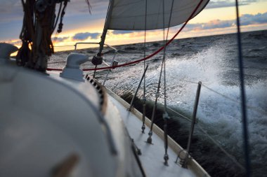 Bir kış günü açık denizde yat gezintisi. Güverteden pruvaya, direğe ve yelkenlere yakın görüntü. Dramatik fırtınalı gökyüzü, kara bulutlar. Destansı deniz manzarası. Kuzey denizi, Norveç
